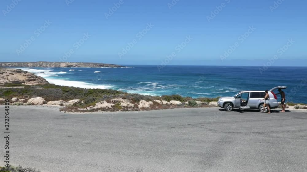 Young couple pack up their car on beautiful clifftop and drive away Young couple pack up their car on beautiful clifftop and drive away