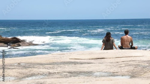 Young couple standing on a rock overlooking the ocean photo