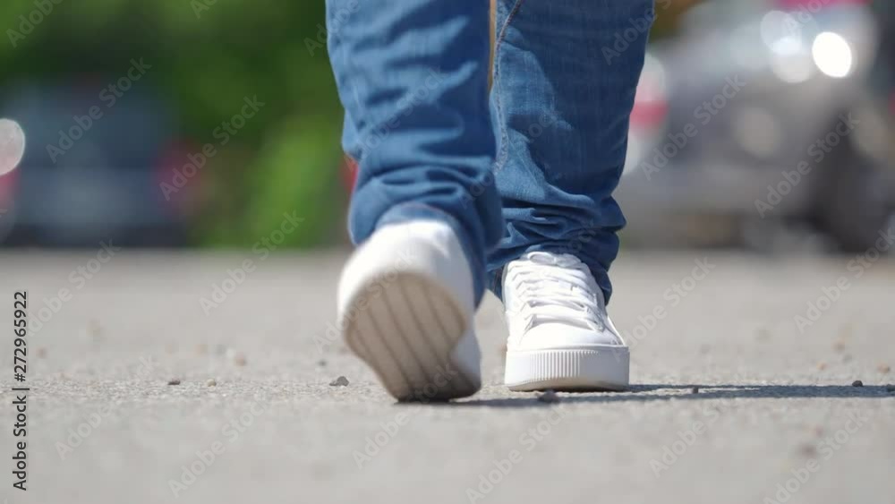 woman in white shoes walking on a parking place. woman in white shoes walking on a parking place.