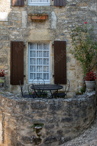 A black metal table and chairs on the romantic terrace of an old stone house in Beynac-et-Cazenac, France