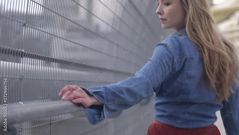 Close up of a young woman walking across a bridge with her hand on railing Close up of a young woman walking across a bridge with her hand on railing