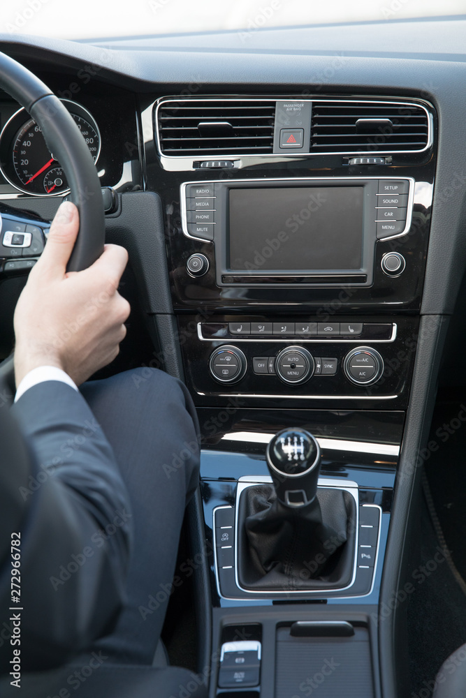 Fototapeta premium Business Mann bedient Autoradio in Mittelkonsole von Mittelklasse-PKW