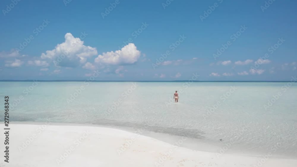 Blonde tourist girl walking into the crystal clear waters of Palawan, Philippines at Onuk Island, Balabac Blonde tourist girl walking into the crystal clear waters of Palawan, Philippines at Onuk Island, Balabac