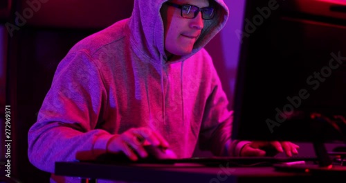 Hacker with a hooded sweathshirt and glasses successfuly hacks a computer and quickly runs off. Shot in 4k 30fps.mov photo