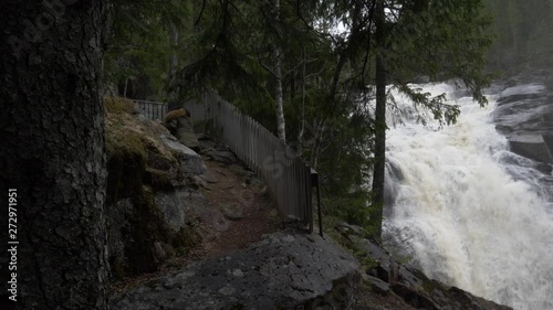 Big waterfall and a girl who walks beside it. photo