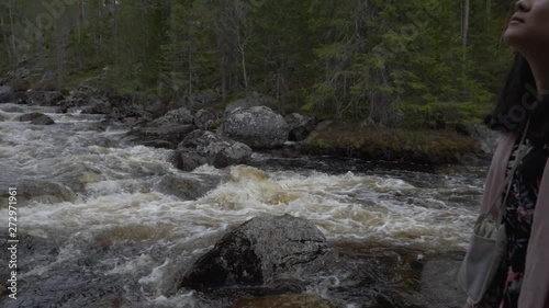 Girl by a a flowing river. Slowmotion photo