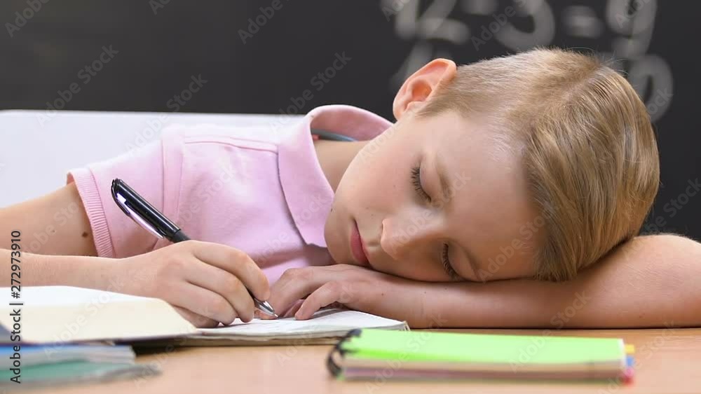 Tired schoolboy sleeping on desk at lesson, exhausted education, overwork Tired schoolboy sleeping on desk at lesson, exhausted education, overwork