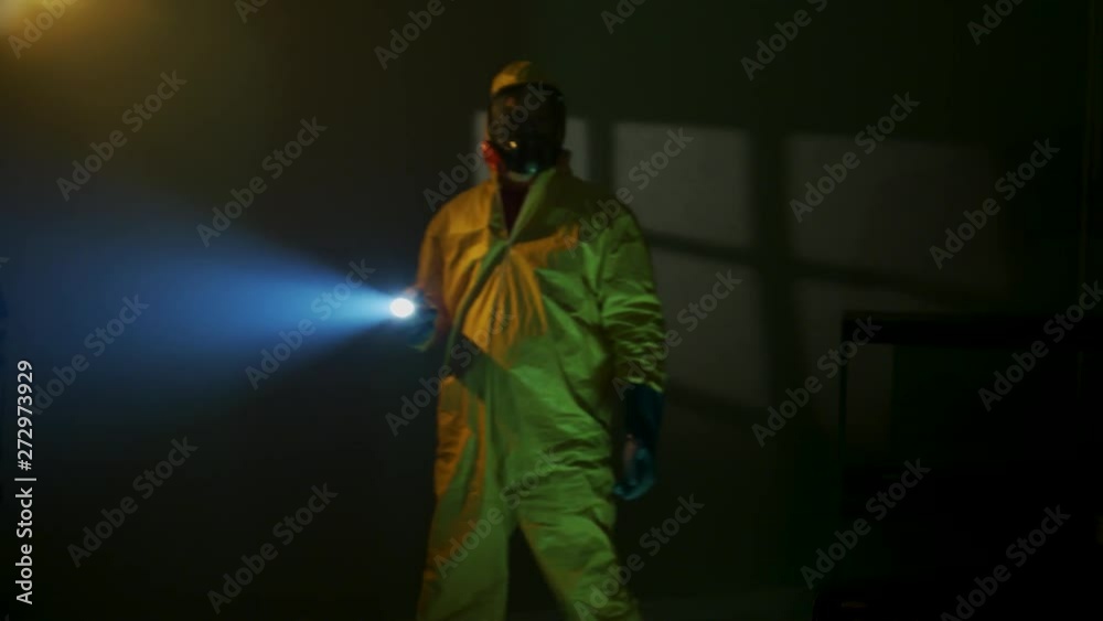 Hazmat suit wearing man explores a dark room Hazmat suit wearing man explores a dark room