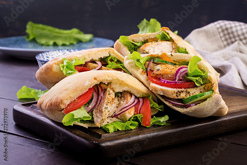 Cuadro en lienzo Pita stuffed with chicken, tomato and lettuce on wooden background