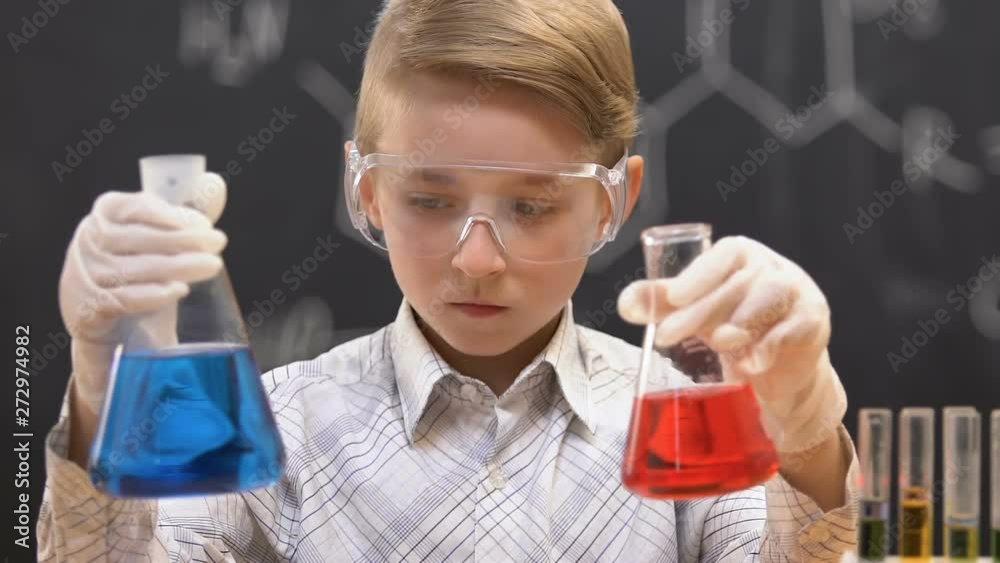 Little scientist comparing flasks with blue and red liquids, experiment result