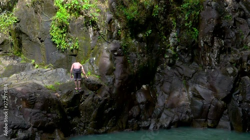 Slow motion shot of a young guy doing an insane backflip into a body of water below, Saut d'Acomat in Guadeloupe photo
