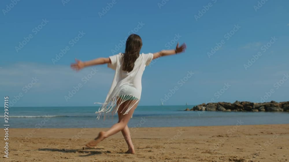 A beautiful young girl dancing on a beach on a sunny day. STATIC SHOT. A beautiful young girl dancing on a beach on a sunny day. STATIC SHOT.