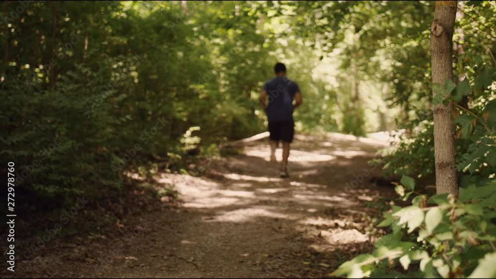 Young man running by camera in forest Young man running by camera in forest