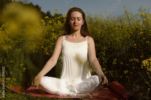 Beautiful girl practices yoga in peaceful nature atmosphere