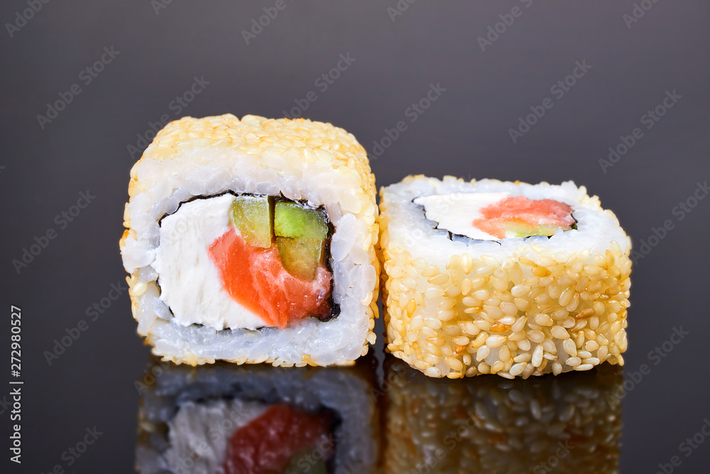 California roll sushi with sesame, salmon, avocado and cream cheese on black background for menu. Japanese food