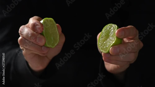 CU SLOW MOTION: Chef squeezes a lime in each hand, makes juices squirt out