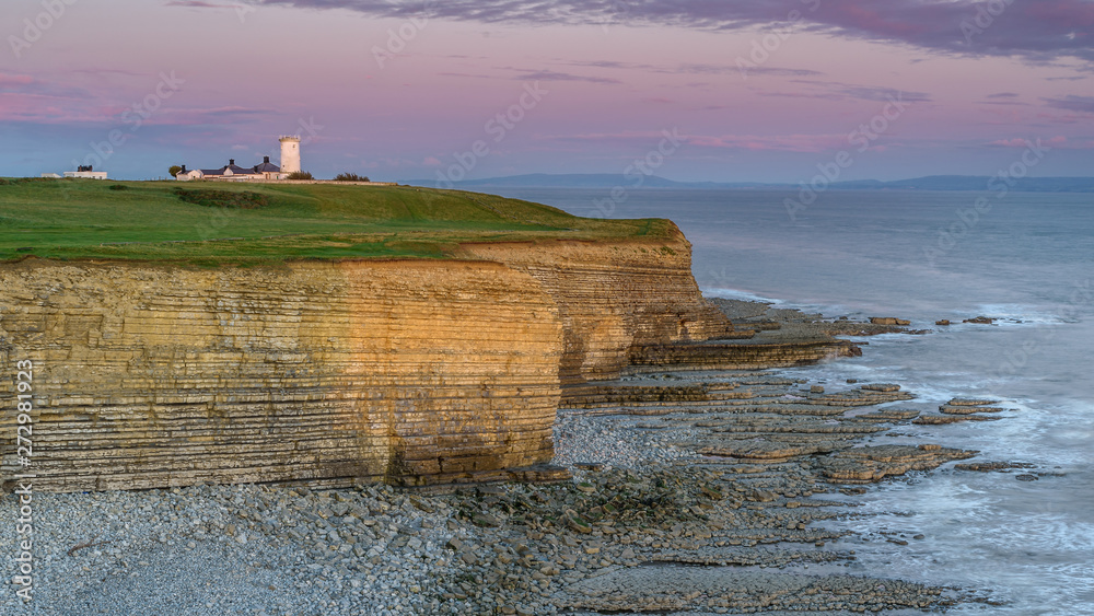 Nash Point lighthouse, south Wales, at sunset.  The lighthouse sits on the top of steep cliffs, overlooking the Bristol Channel
