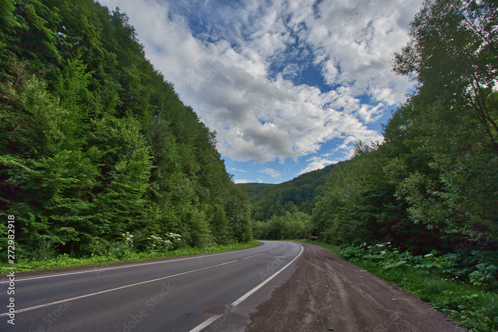 The road to the mountains. Poor quality asphalt pits and green trees The road to the mountains. Poor quality asphalt pits and green trees