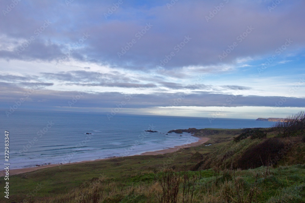 Scenic Irish Coastline / Beach with Green Flields at Sunset