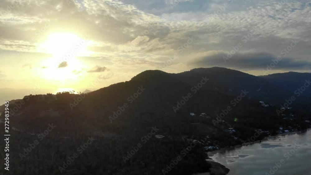 Static shot top view shot of a tropical island mountain with the sun setting behind the clouds Static shot top view shot of a tropical island mountain with the sun setting behind the clouds