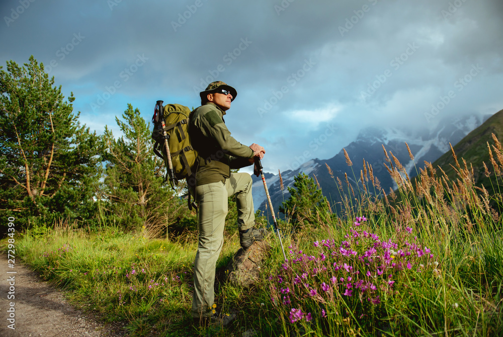 man tourist with backpack  trekking poles travels in the mountains