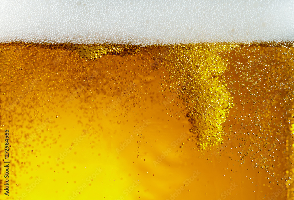 Close up view of floating bubbles in light golden colored beer background. Texture of cooling summer's filtered drink with foam and macro fizz on the glass wall. Fizzing or floating up to top of Close up view of floating bubbles in light golden colored beer background. Texture of cooling summer's filtered drink with foam and macro fizz on the glass wall. Fizzing or floating up to top of