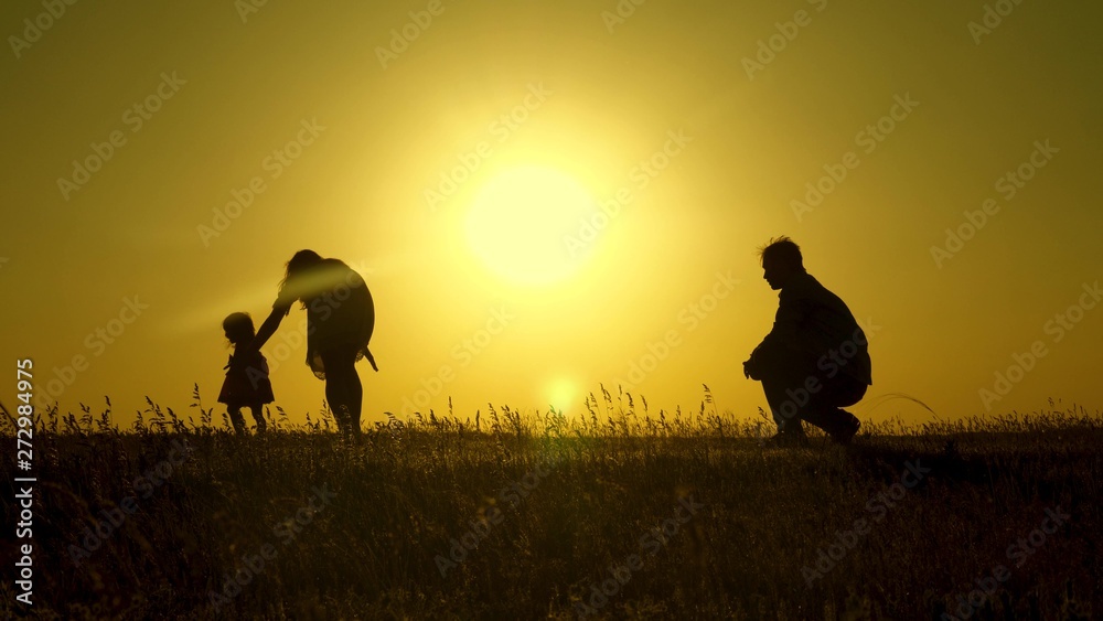 parents play with their little daughter. mother and Dad play with their daughter in sun. happy baby goes from dad to mom. young family in field with a child 1 year. family happiness concept.