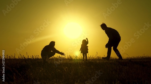 parents play with their little daughter. mother and Dad play with their daughter in sun. happy baby goes from dad to mom. young family in field with a child 1 year. family happiness concept.