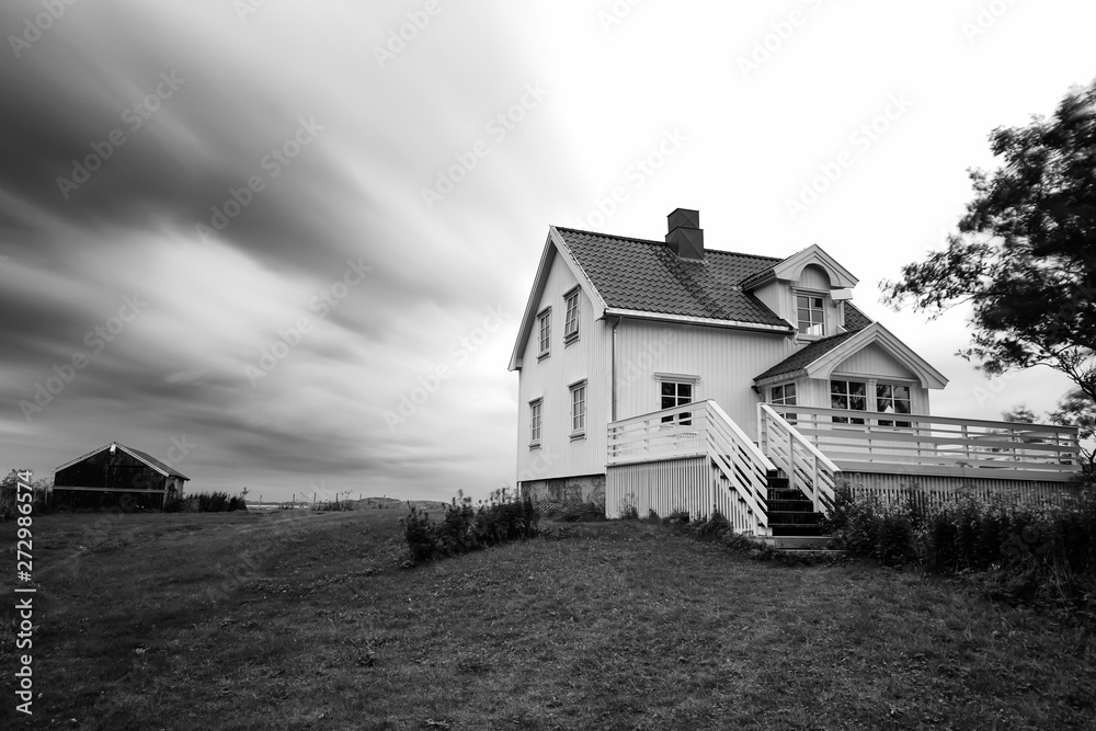 White wooden Scandinavian house, Rorbu, clouds in slow motion. Black&white photography. White wooden Scandinavian house, Rorbu, clouds in slow motion. Black&white photography.