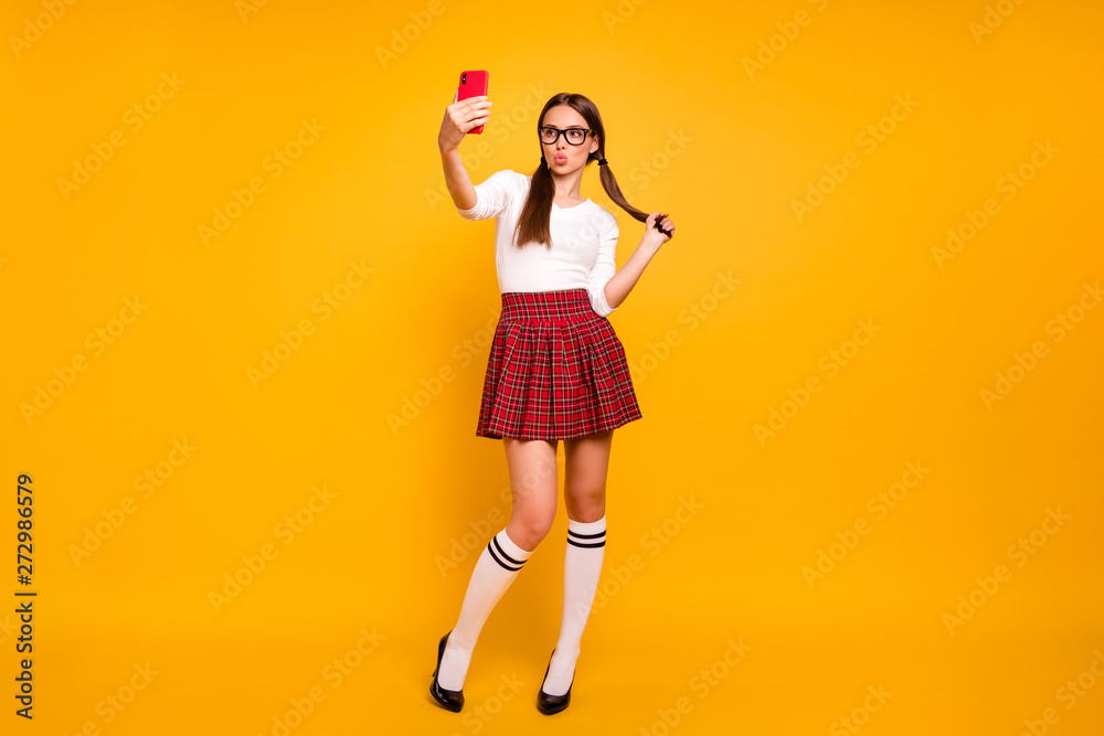 Full length body size view portrait of nice attractive lovely funky cheerful girl wearing uniform holding in hands cell making taking selfie plump lips isolated on bright vivid shine yellow background Full length body size view portrait of nice attractive lovely funky cheerful girl wearing uniform holding in hands cell making taking selfie plump lips isolated on bright vivid shine yellow background