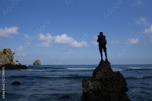 A photographer climbed onto the rocks on a beach to capture photos of Koka's beach landscape, Flores, Indonesia