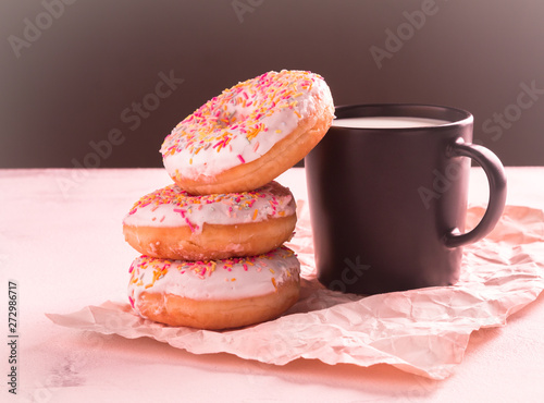 American sweetness glazed donuts and a cup of milk on a gray surface on a black background close-up with space for your text
