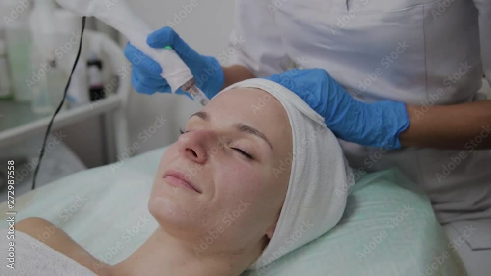 Professional cosmetologist performs DermaPen procedure in a cosmetology clinic.