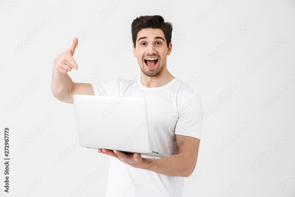 Happy excited young man posing isolated over white wall using laptop computer pointing. Happy excited young man posing isolated over white wall using laptop computer pointing.