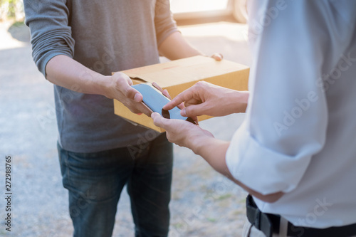 customer hands appending signature in mobile phone, man receiving parcel post box from courier with delivery service man, express delivery, online shopping concept
