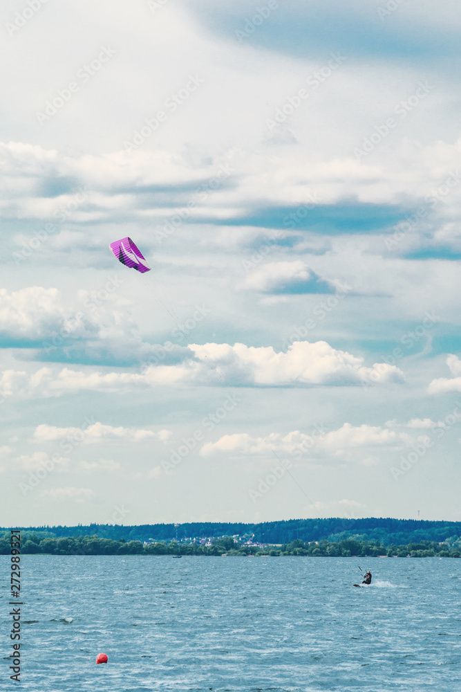 A kiteboarder is pulled across water by a power kite. Kitesurfer high in flight