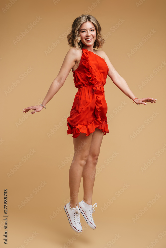 Full length photo of cute european woman 20s wearing red dress smiling and jumping Full length photo of cute european woman 20s wearing red dress smiling and jumping