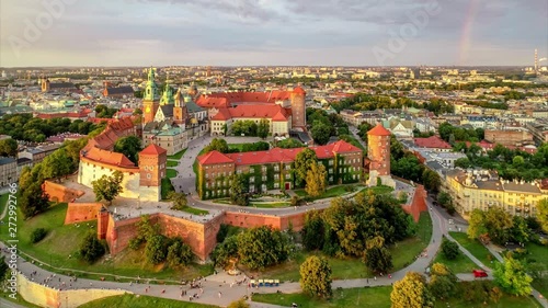 Historic royal Wawel Cathedral and castle in Cracow, Poland, in red sunset light with a rainbow, Vistula river, park and promenade. Aerial 4K approaching video at sunset in summer