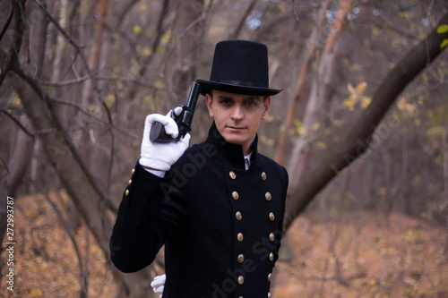 Fotografie A man with a gun in the clothes of the nineteenth century in a gloomy forest