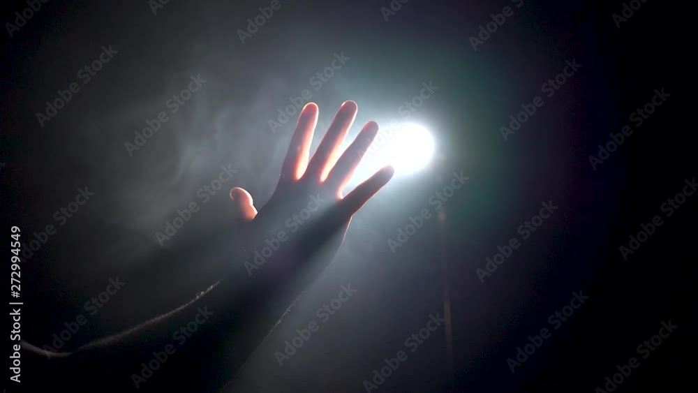man hand touches the light in the dark