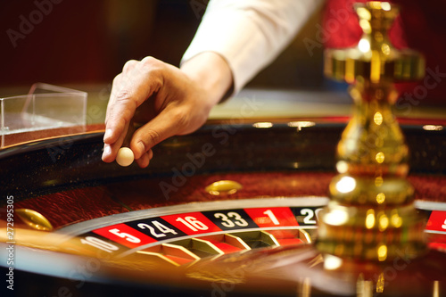 Canvas Print The croupier holds a roulette ball in a casino in his hand.