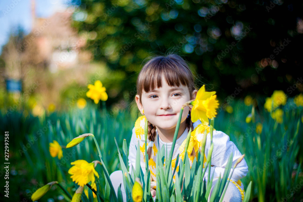 Adorable little toddler girl with a white teddy bear having fun in summer park on beautiful sunny day with yellow flowers in the background Adorable little toddler girl with a white teddy bear having fun in summer park on beautiful sunny day with yellow flowers in the background