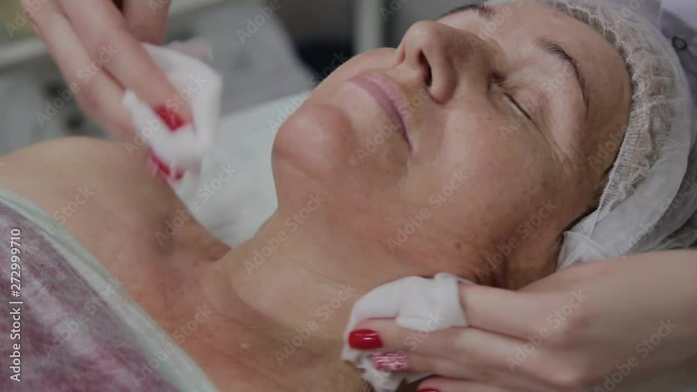 Beautician performs the procedure of washing the face of an elderly woman in a cosmetology clinic. Beautician performs the procedure of washing the face of an elderly woman in a cosmetology clinic.