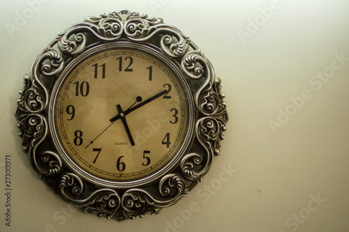 Ancient Wall Designer Wall Clock With Light Yellow Back Ground showing time 05:10 o'clock