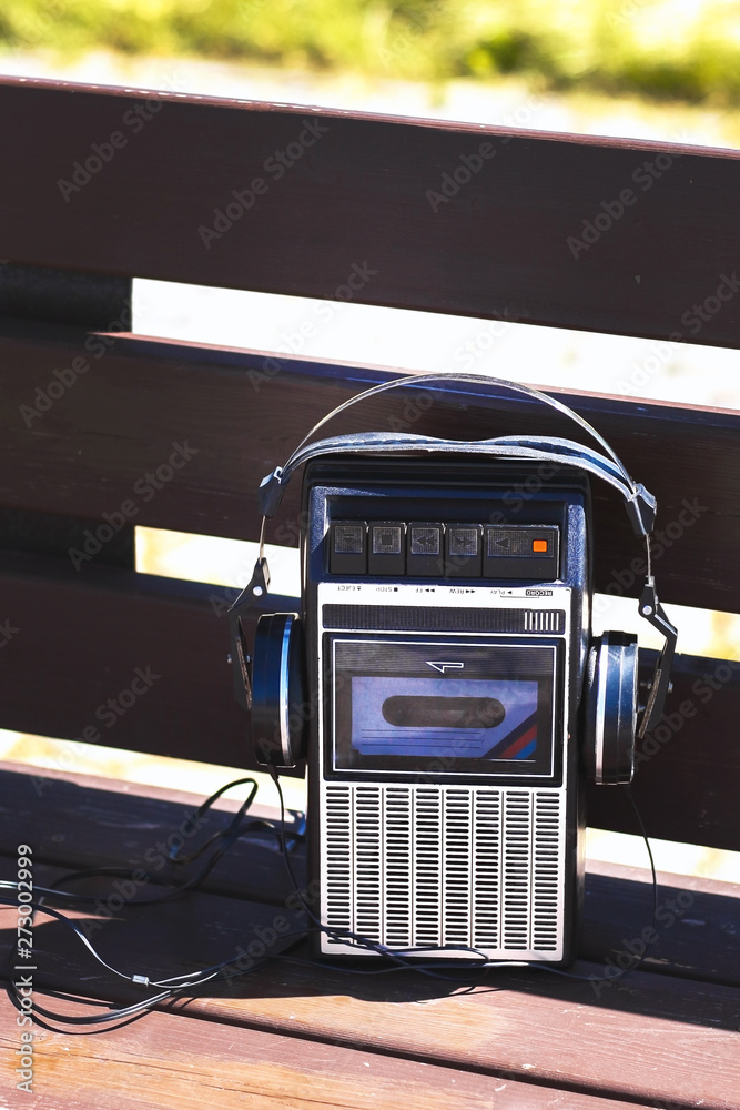Retro vintage old 80s , 90s style portable radio audio cassette recorder  player with audio tape cassette inside with retro headphones on bench Stock  Photo | Adobe Stock