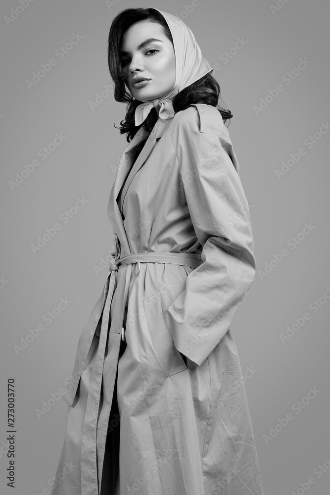 Naklejka premium Young elegant brunette woman in coat and shawl posing in studio