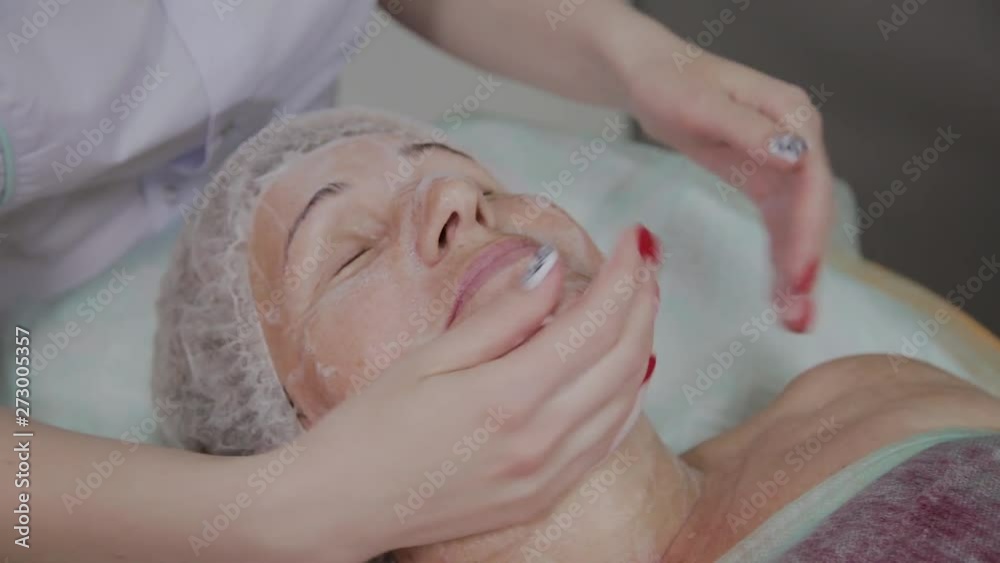 Female cosmetologist doing face massage to elderly woman in cosmetological clinic. Female cosmetologist doing face massage to elderly woman in cosmetological clinic.
