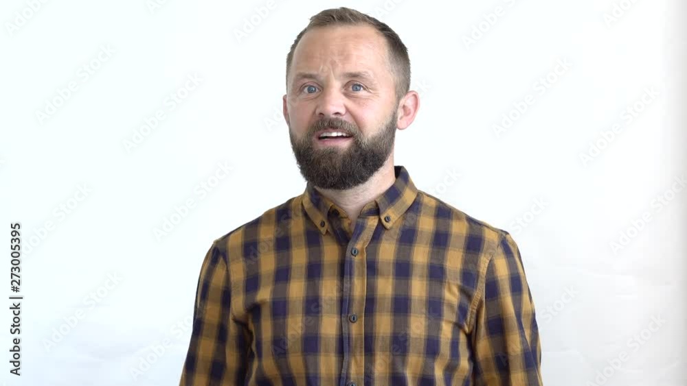 concept - emotions. close-up of a bearded man in a plaid shirt on a white background ironically showing facial expressions conditional signal in the form of a blinking eye. concept - emotions. close-up of a bearded man in a plaid shirt on a white background ironically showing facial expressions conditional signal in the form of a blinking eye.