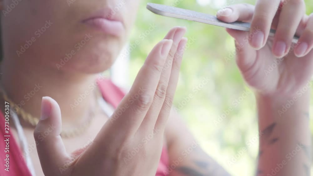Close-up portrait African American woman sitting on the window sill cutting nails with a nail file. The girl caring about herself. Happy girl relaxing at home. Day off of the lady Close-up portrait African American woman sitting on the window sill cutting nails with a nail file. The girl caring about herself. Happy girl relaxing at home. Day off of the lady