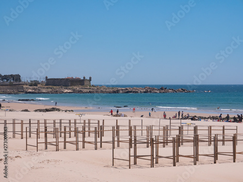 Beach in Matosinhos, Porto, Portugal with beach hut frames in foreground and Cheese Castle fort in background © Barry